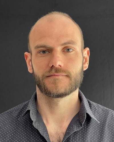 Portretfoto van Piet Baudoin: man met korte baard in een donkerblauw gestippeld overhemd